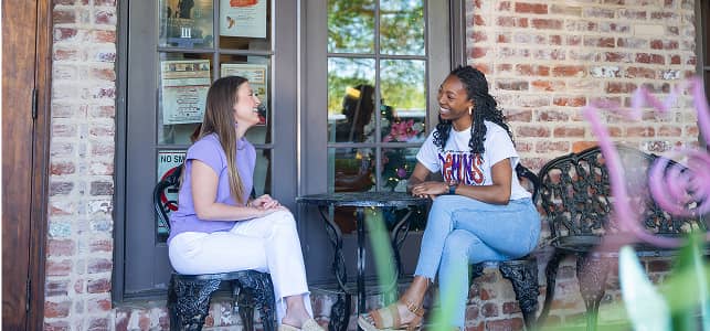 NSULA students talking and laughing at a table on campus