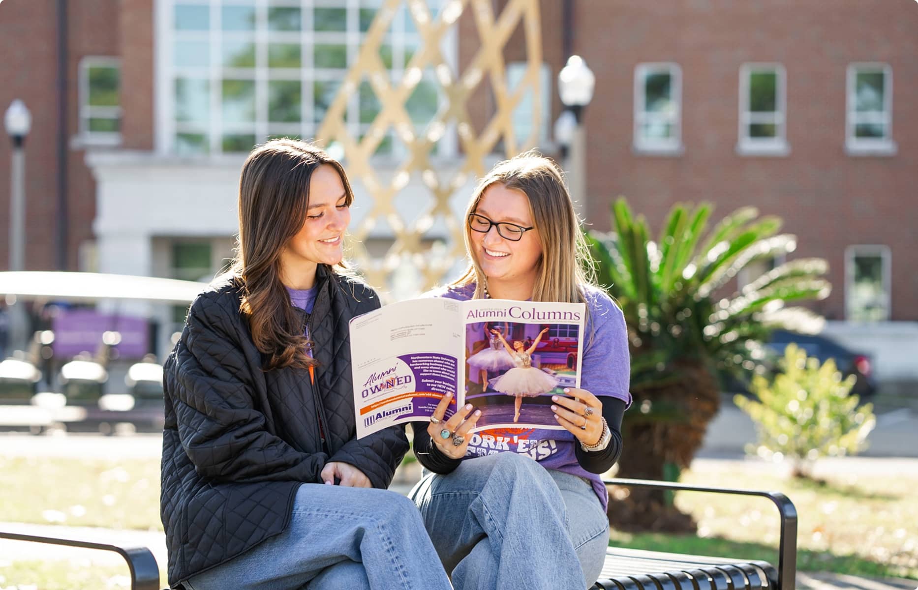 NSULA Students reading a branded book on bench on campus