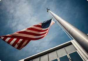 American flag flying in the wind off a pole next to the NSULA building