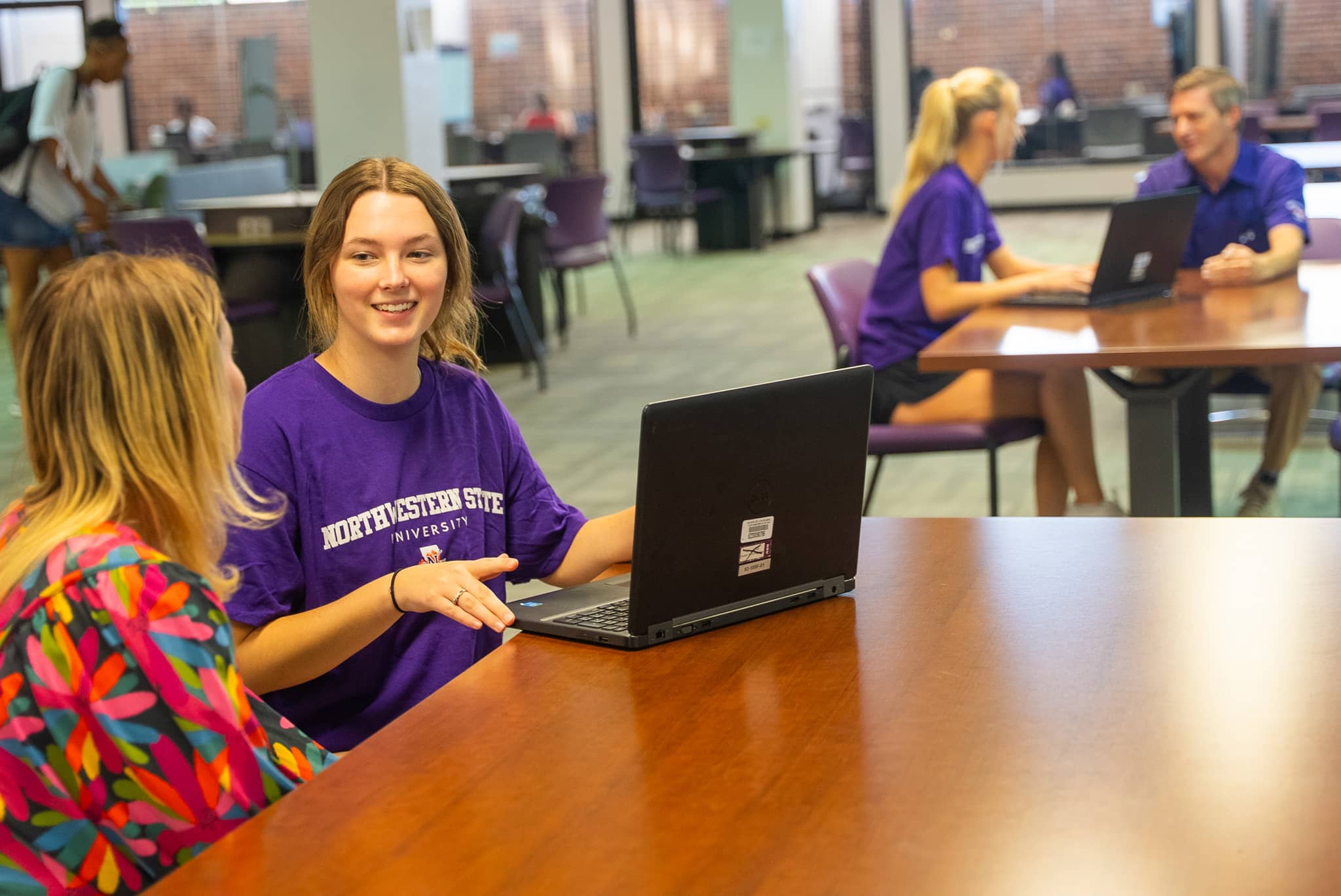 Students in Library talking with a laptop on NSULA campus