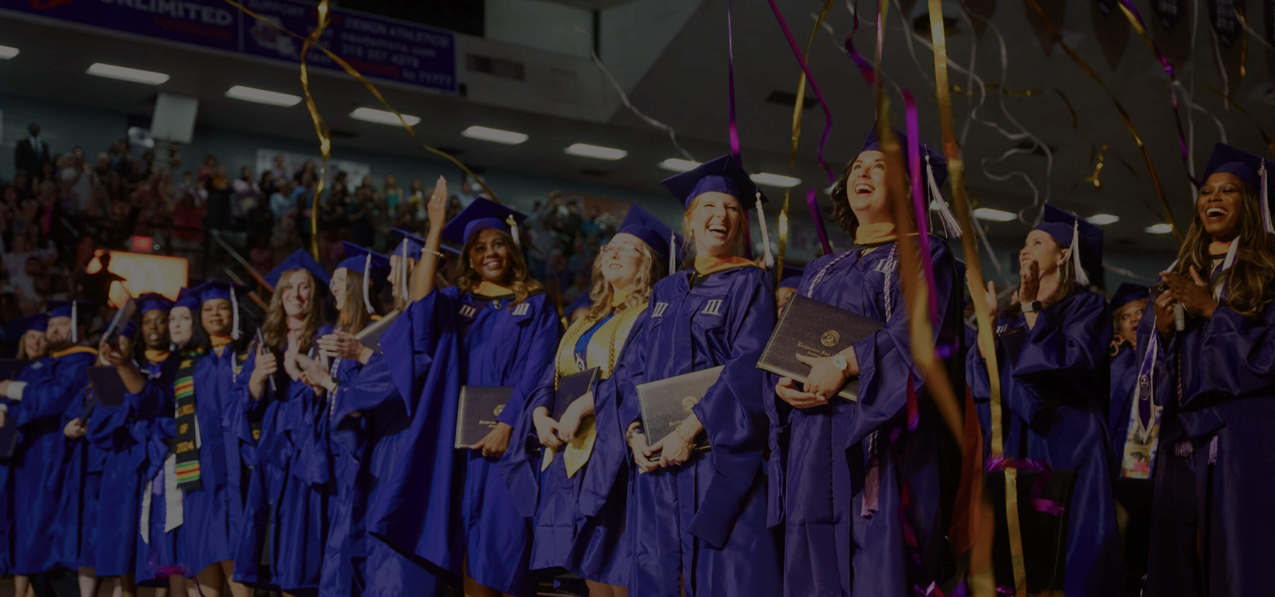 A graduation ceremony with students in purple robes celebrating.