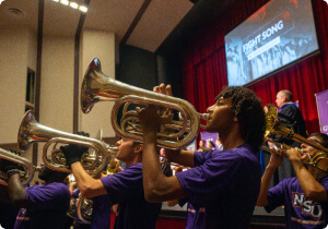 Students playing brass instruments in a performance.