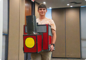 A student holding a large model train.