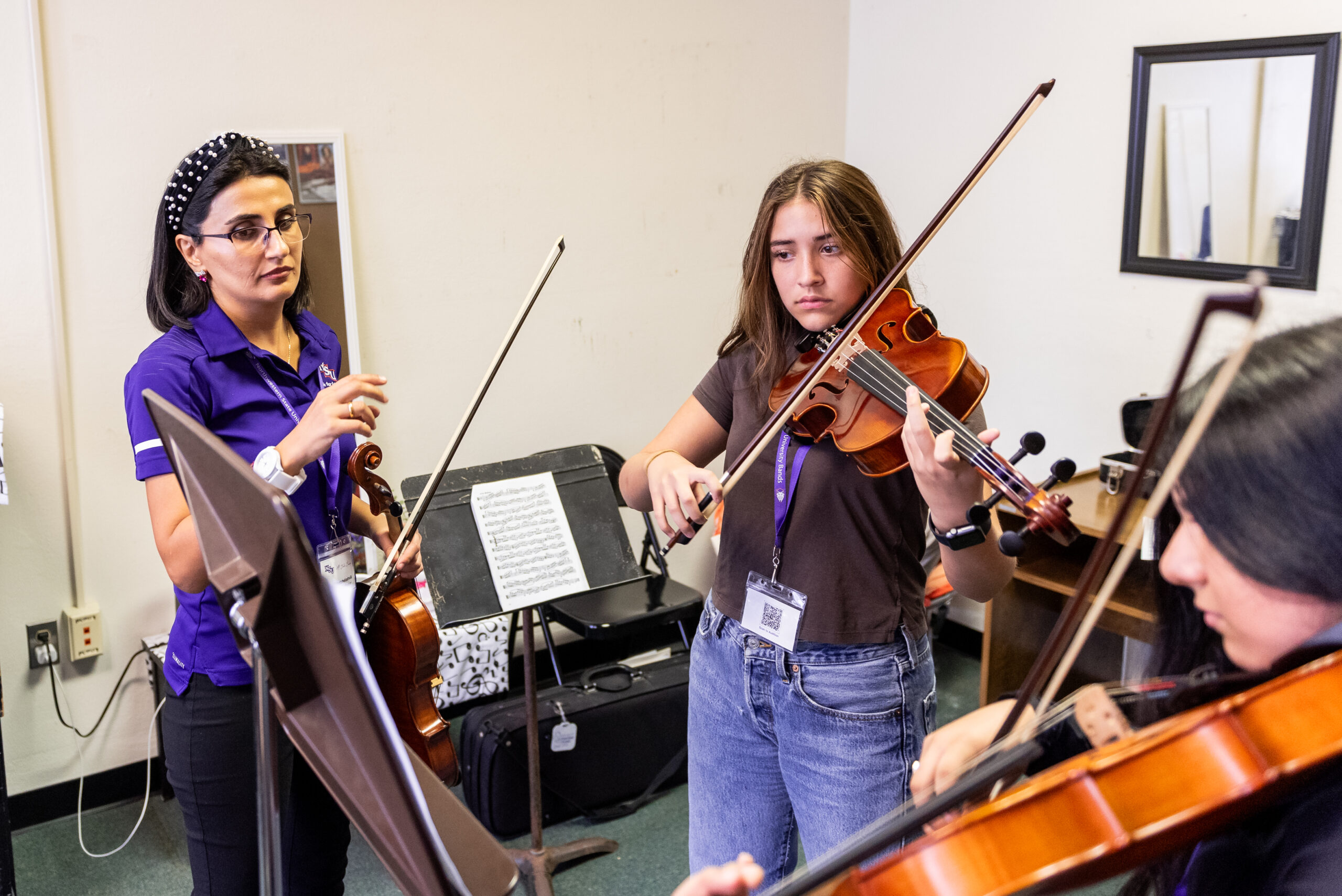 Music instructor helps NSU student with string instrument piece