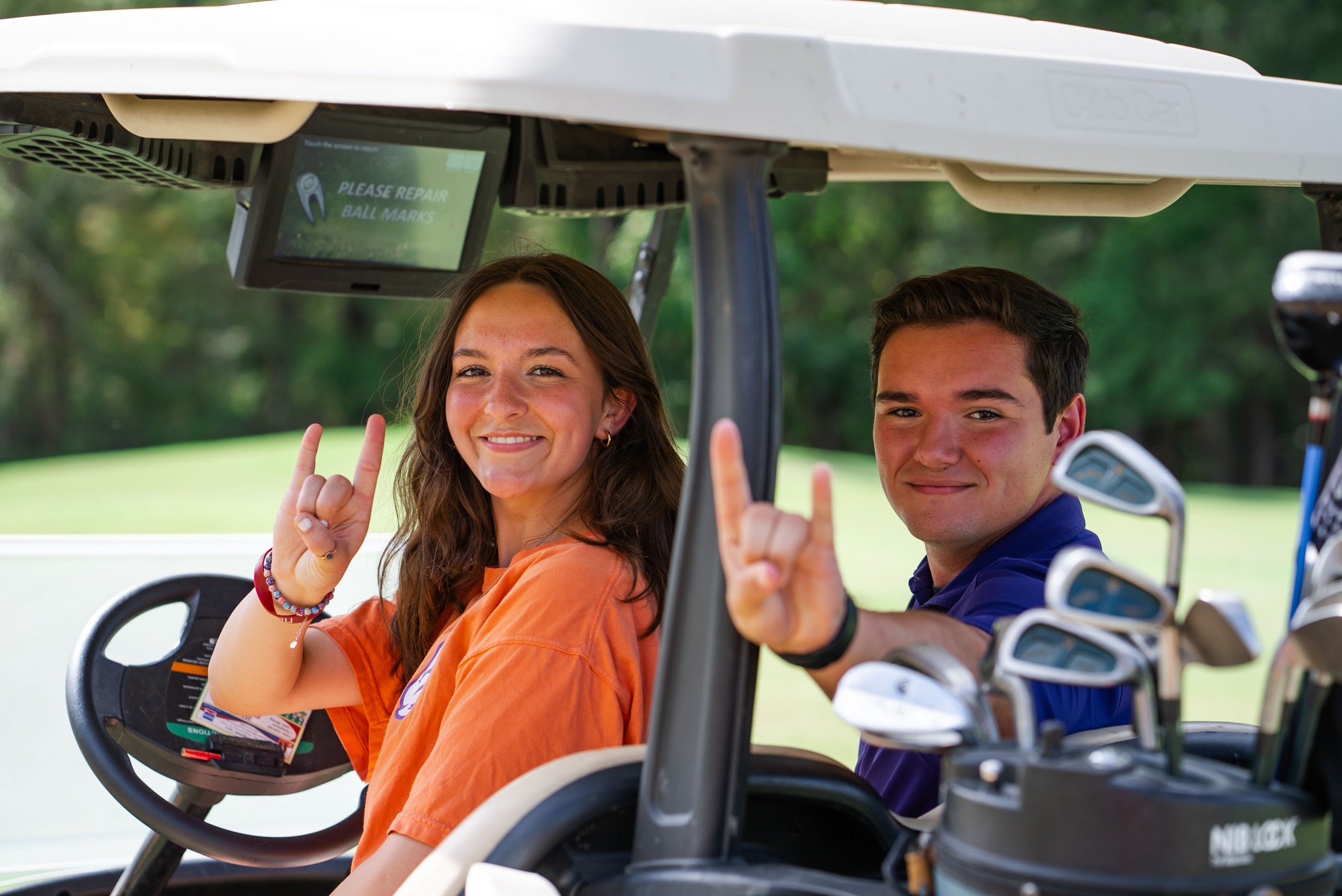 2 NSU students pose for a photo on a golf cart on the course