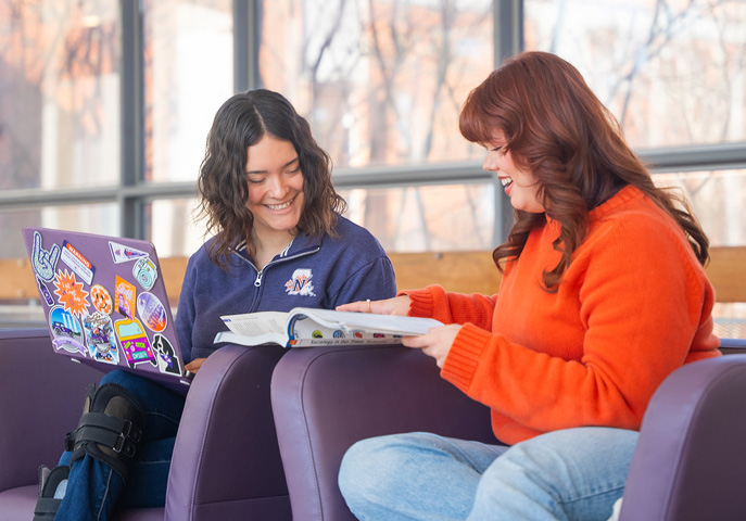 NSU students sitting in chair studying with laptop.