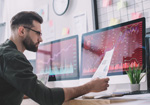 Man at computer screen analyzing documents and data.