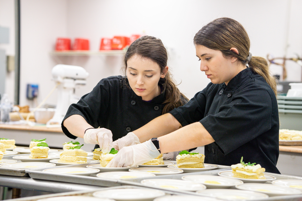 NSU culinary students work together to plate a dish in the kitchen
