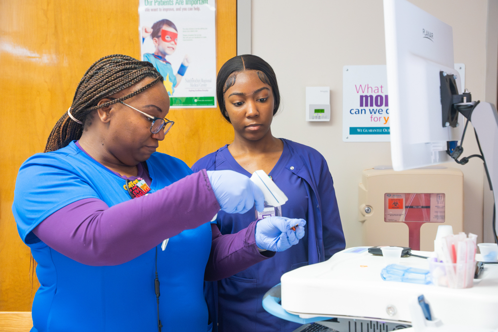 NSU nursing student learning from instructor in hospital