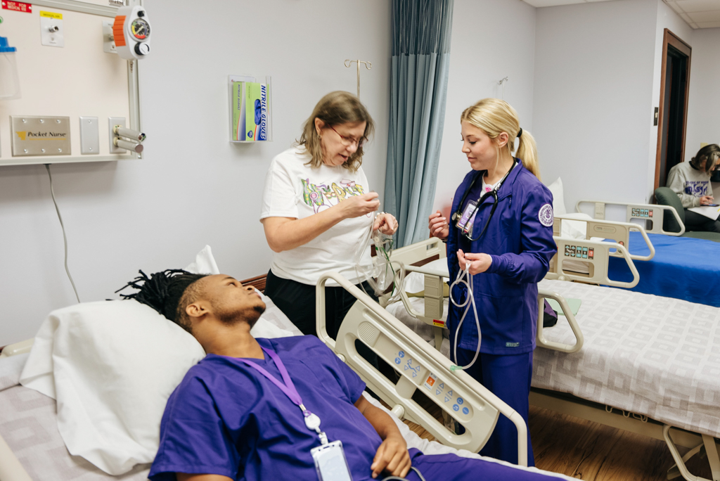 NSU faculty member assisting two NSU nursing students.