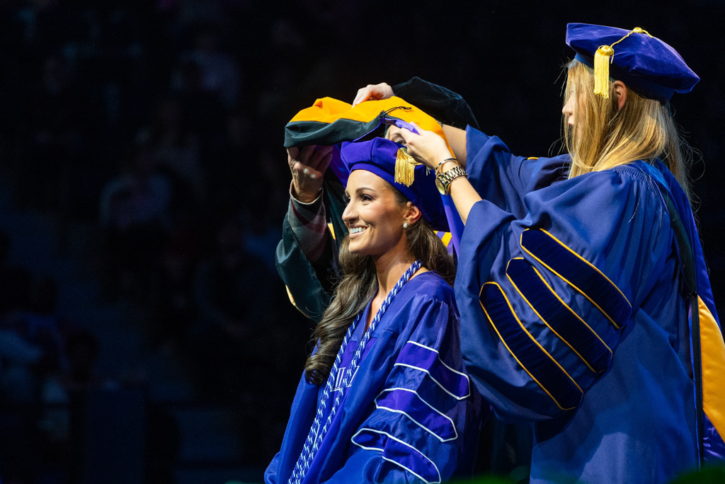 A doctoral nursing graduate receives her hood at commencement