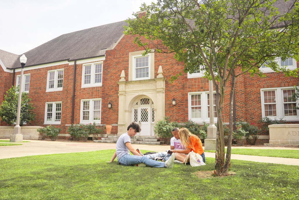 3 NSU students study on the lawn of Caspari Hall