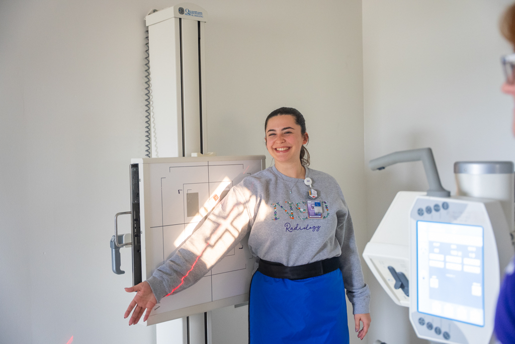 NSU student smiles for a photo as other students perform practice x-rays