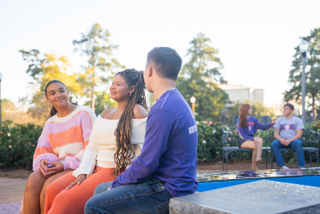 A group of NSU students sit outdoors on campus