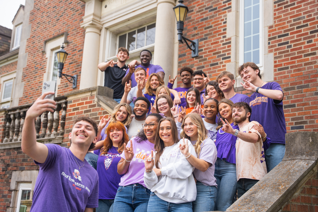 A group of NSU students take a photo on the steps outside of Russell Hall