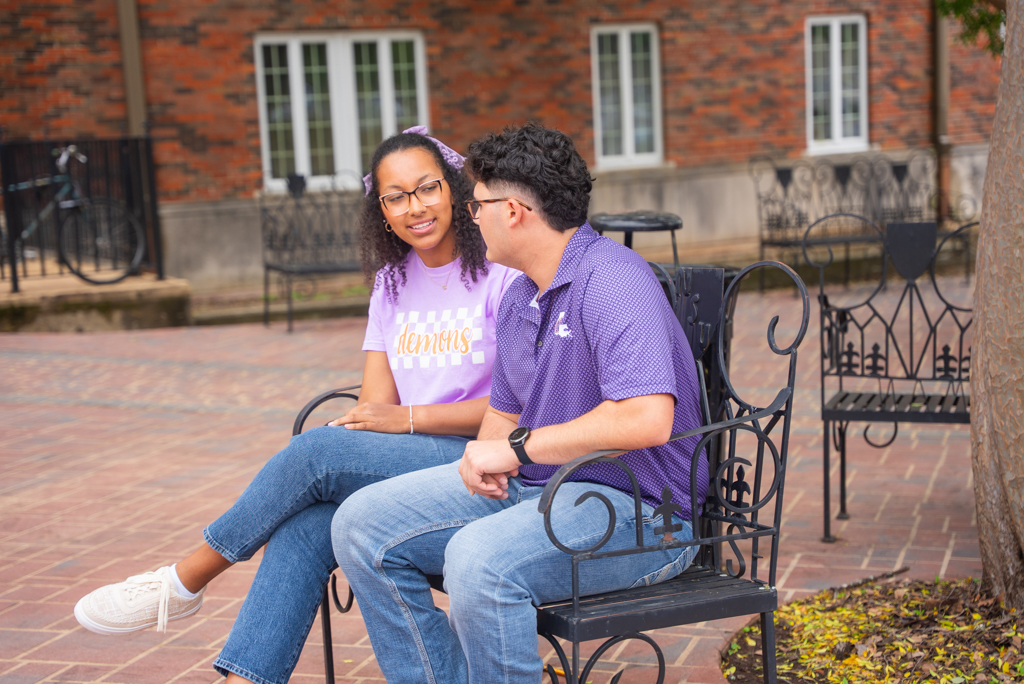 NSU students sit on a bench outside Russell Hall