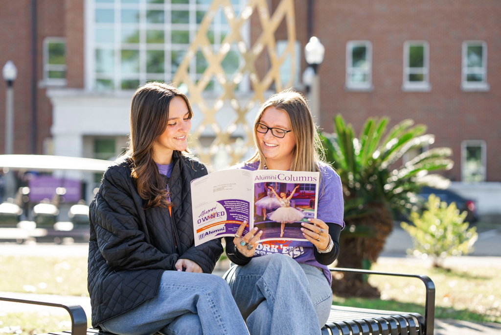 NSU students read the Alumni Columns on a campus bench