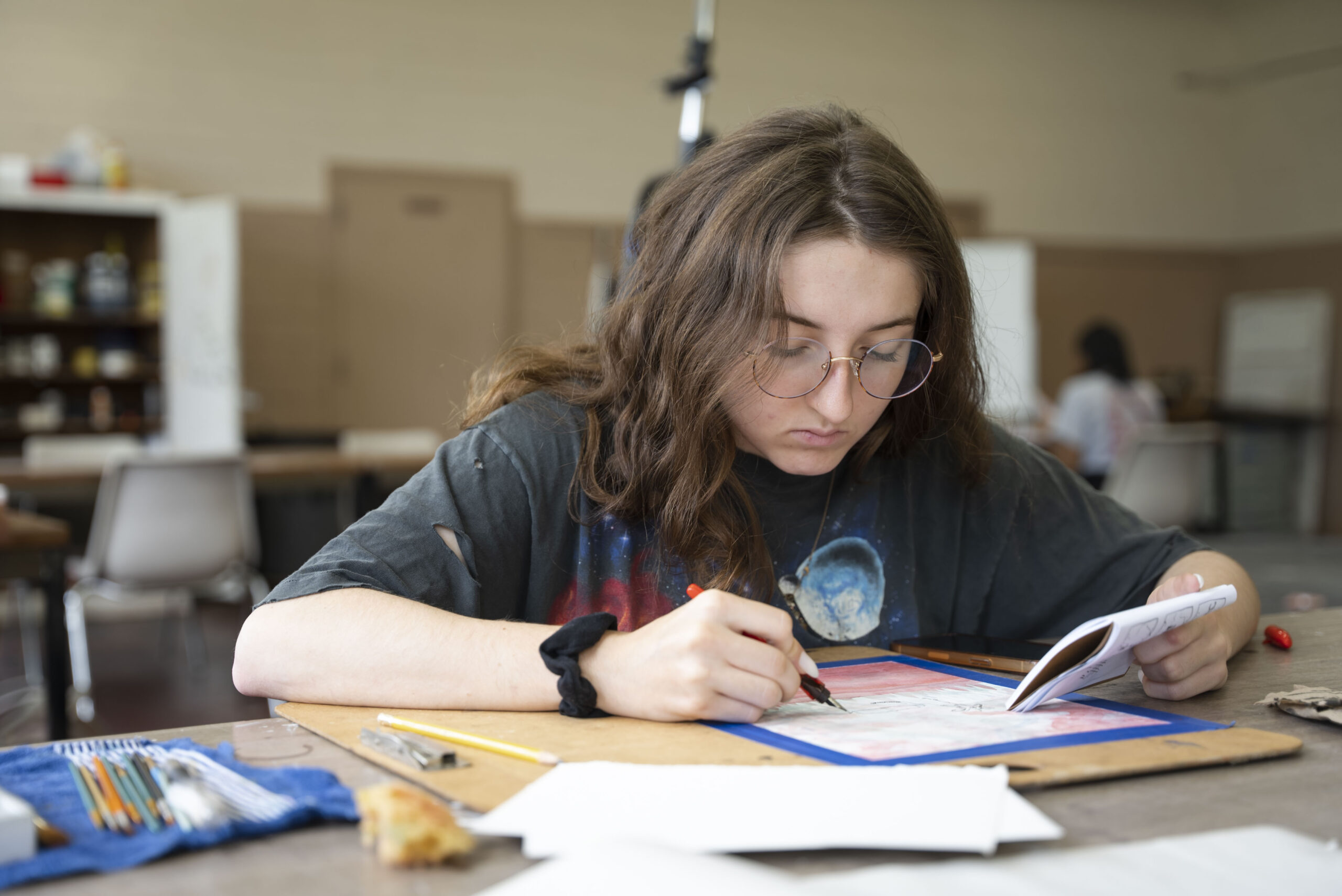 NSU student sketches on paper in classroom