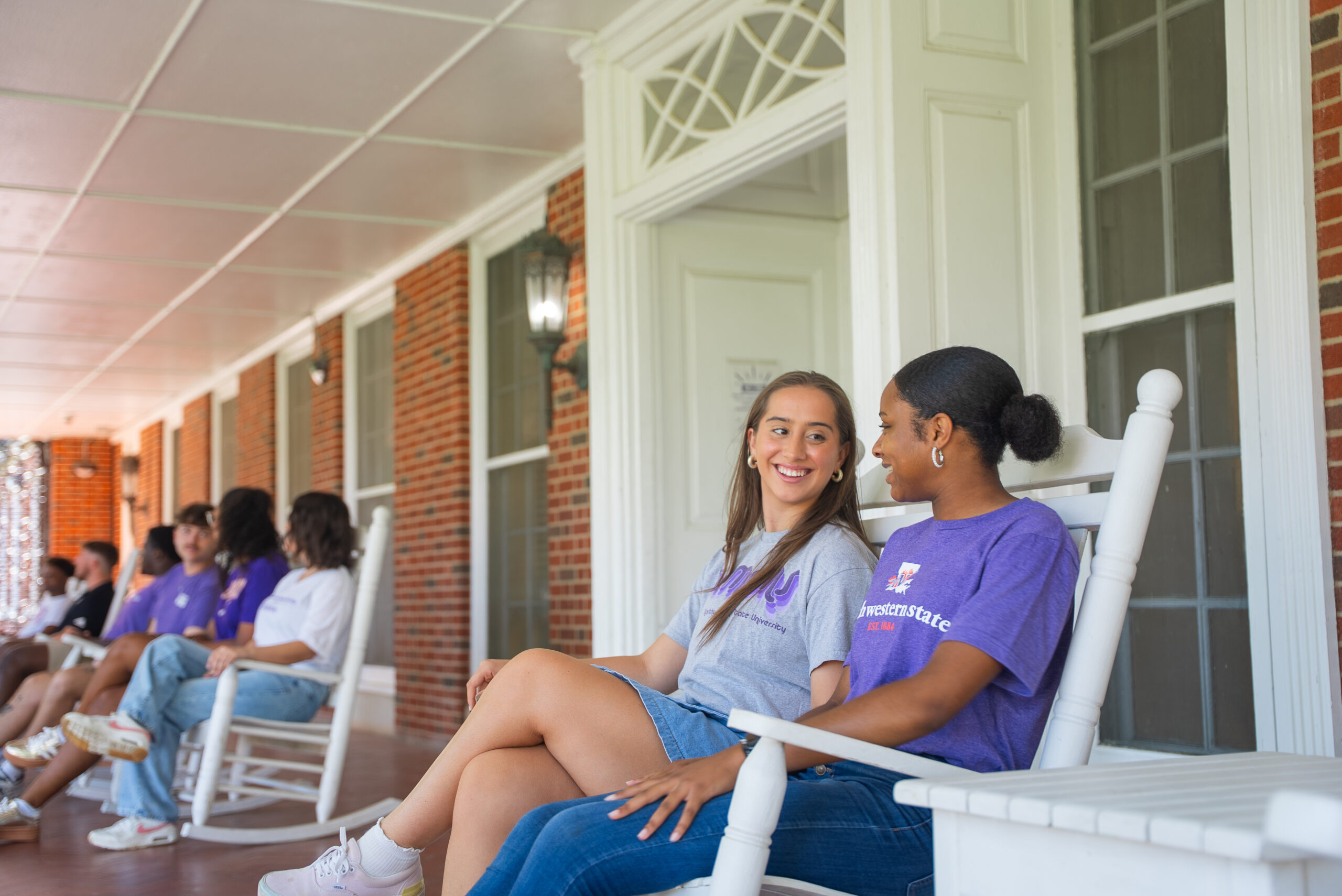 Students sit in rocking chairs at Varnado Hall