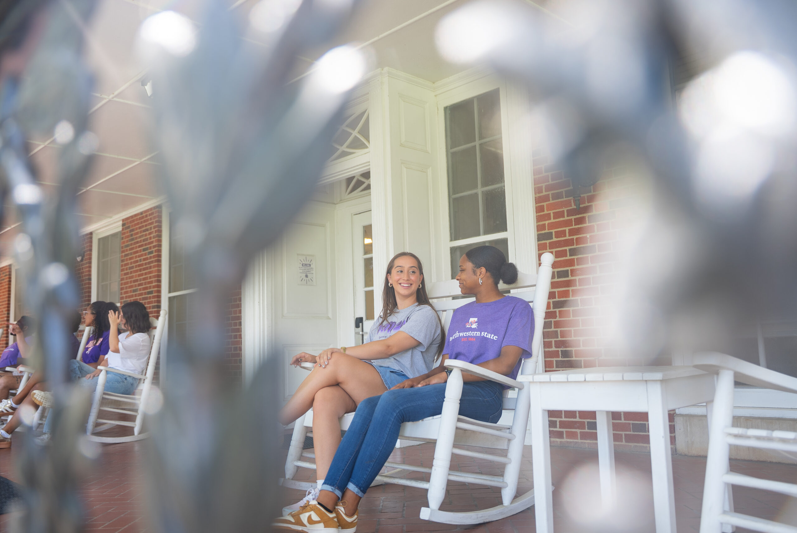 Students sit in rocking chairs at Varnado Hall