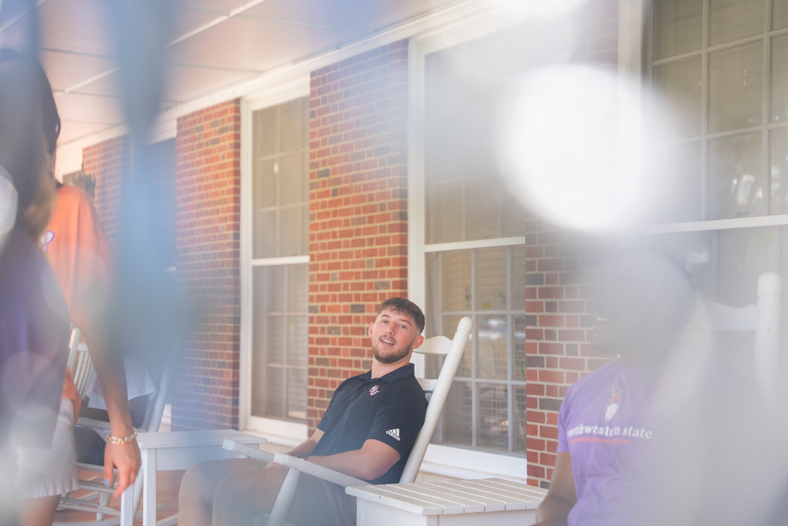 Students sit in rocking chairs at Varnado Hall