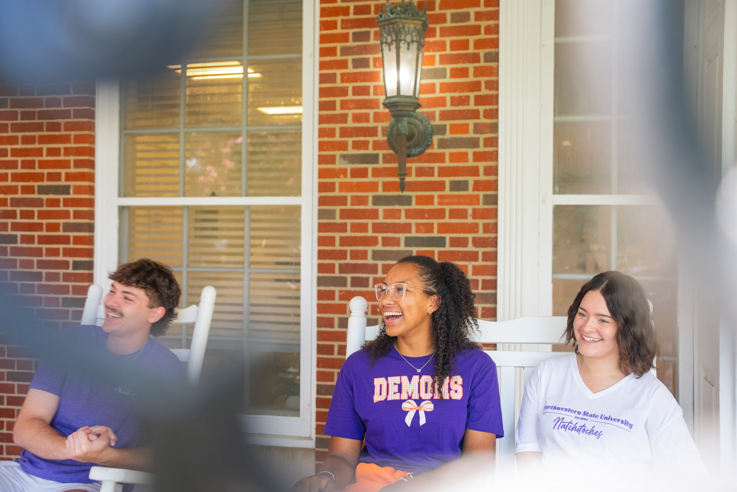 Students sit in rocking chairs at Varnado Hall