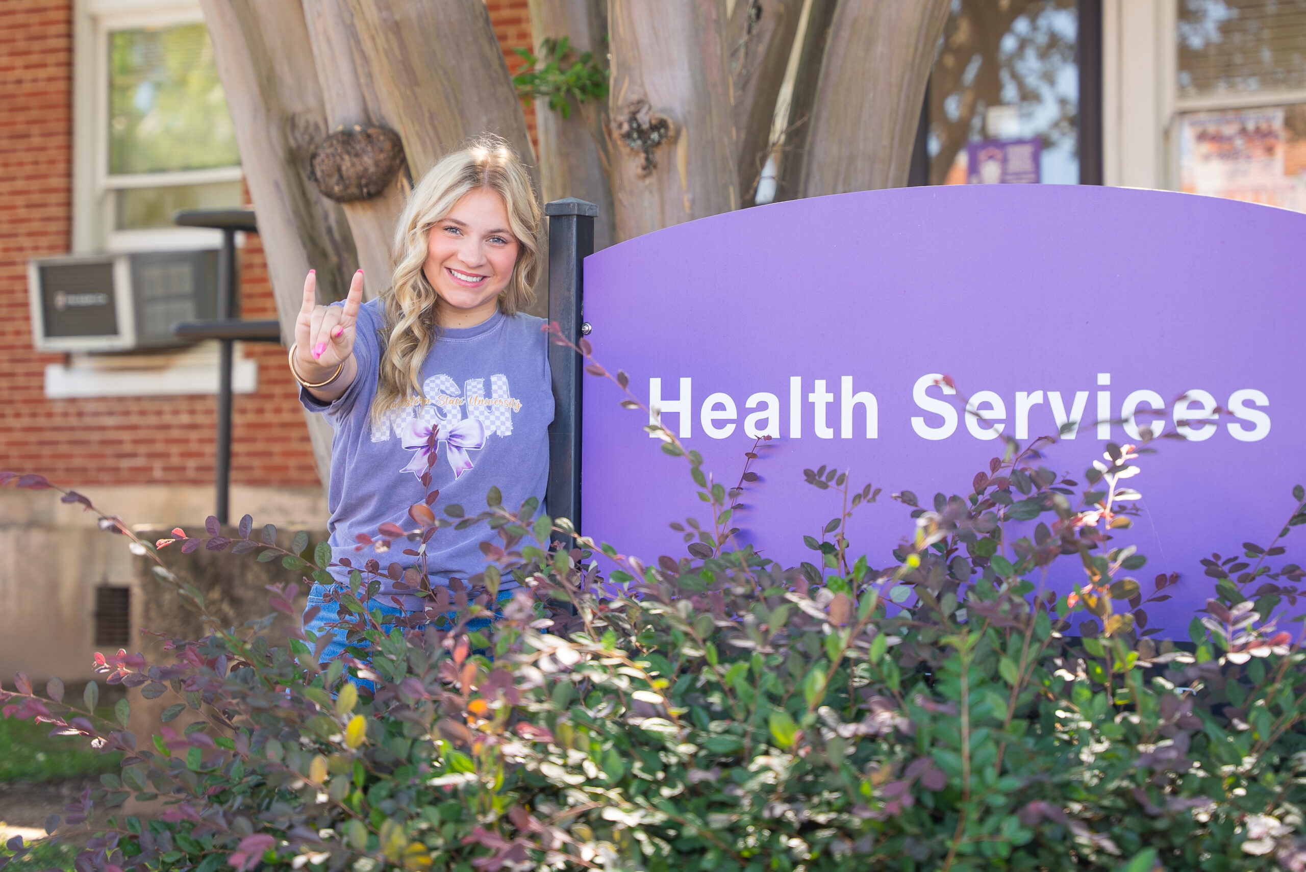 NSU student stands next to Health Services sign