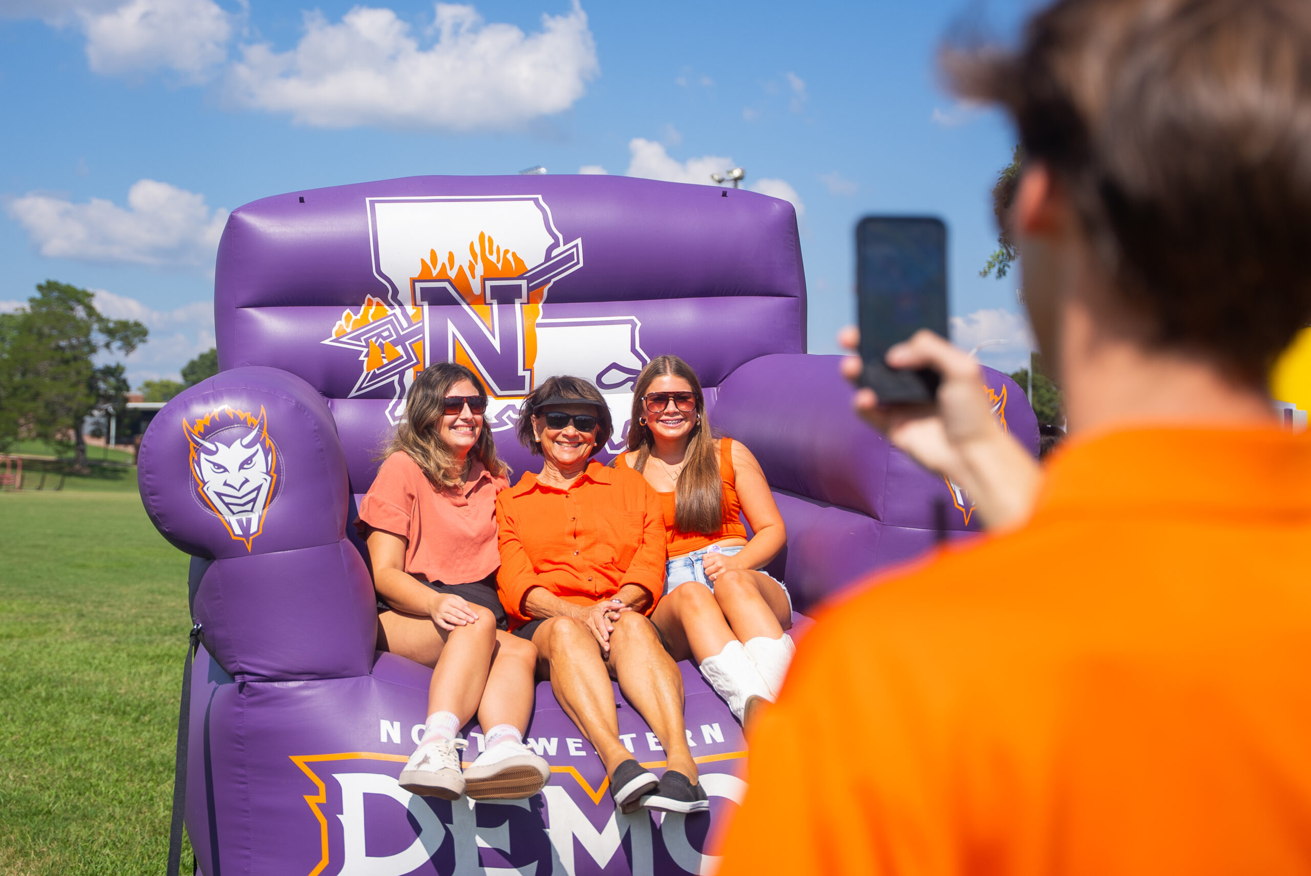 NSU Family Day; students enjoying time in the big NSU chair.