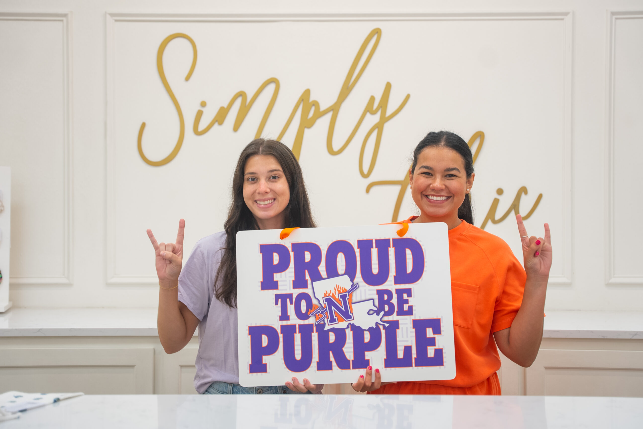 NSU alumnae pose for a photo in a local boutique, holding a NSU door hanger