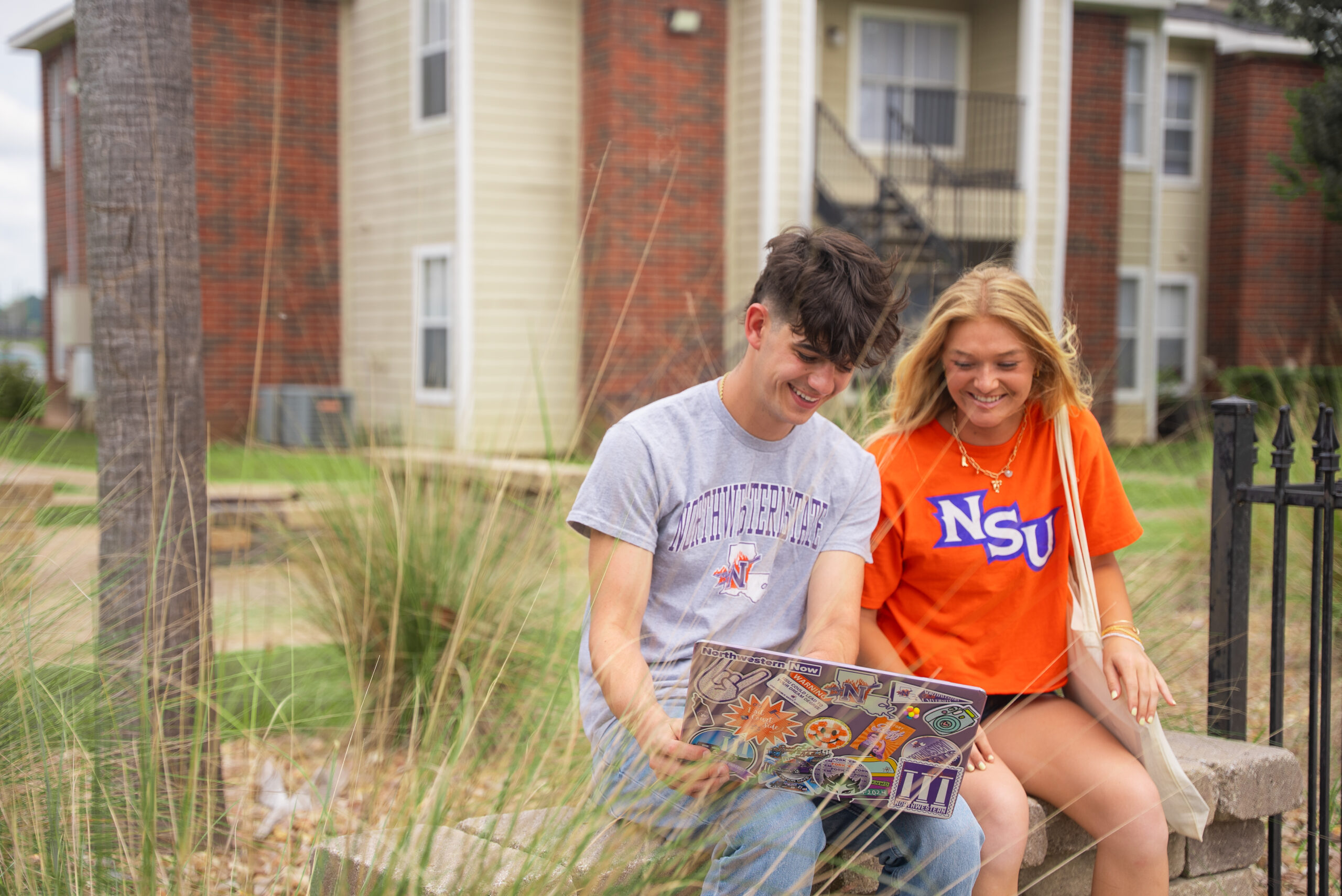 NSU students sit on a bench outside of residential community