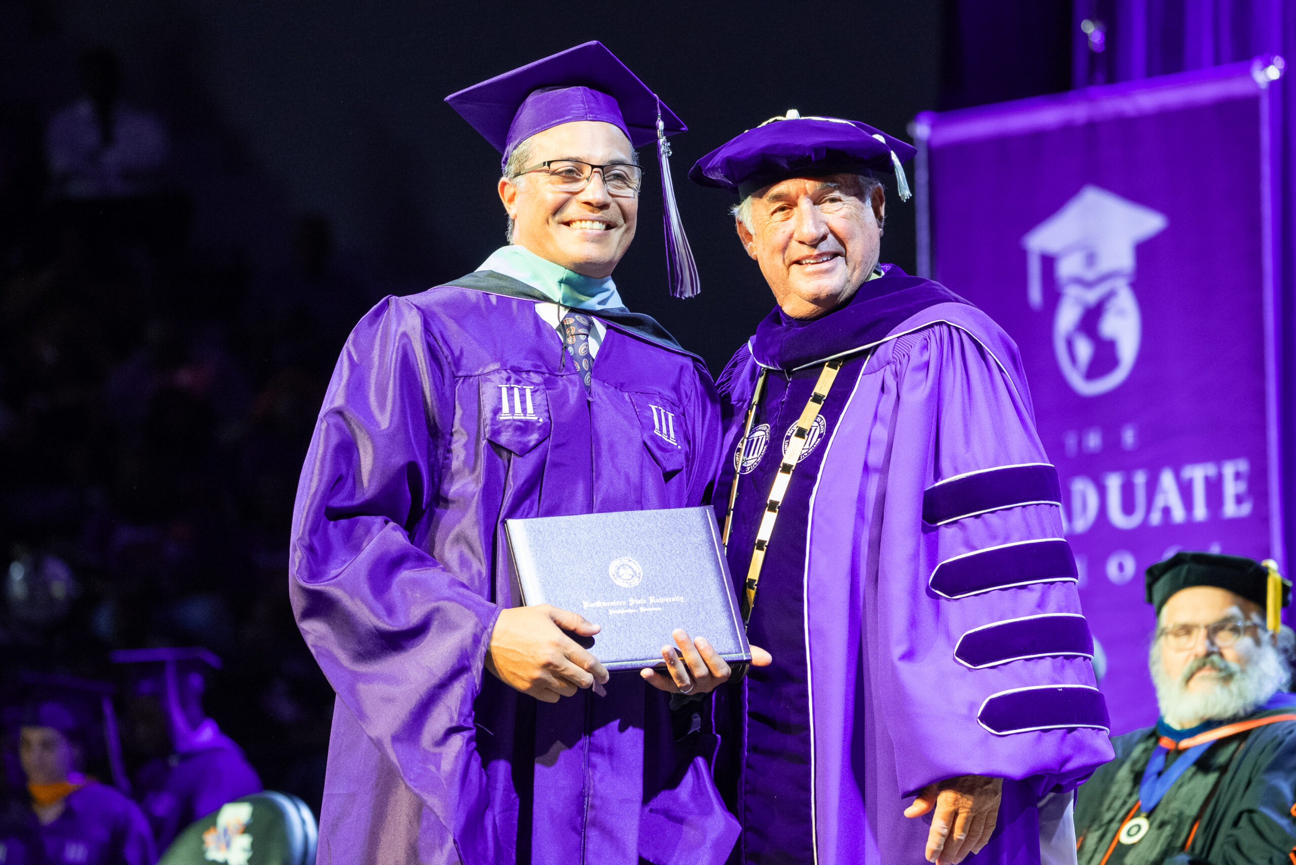 NSU Master's graduate poses for a photo on stage