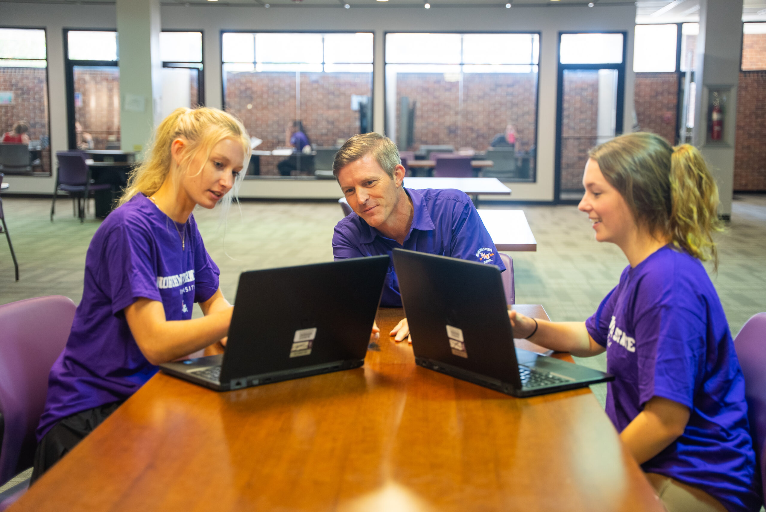 NSU staff member helps two students in the library