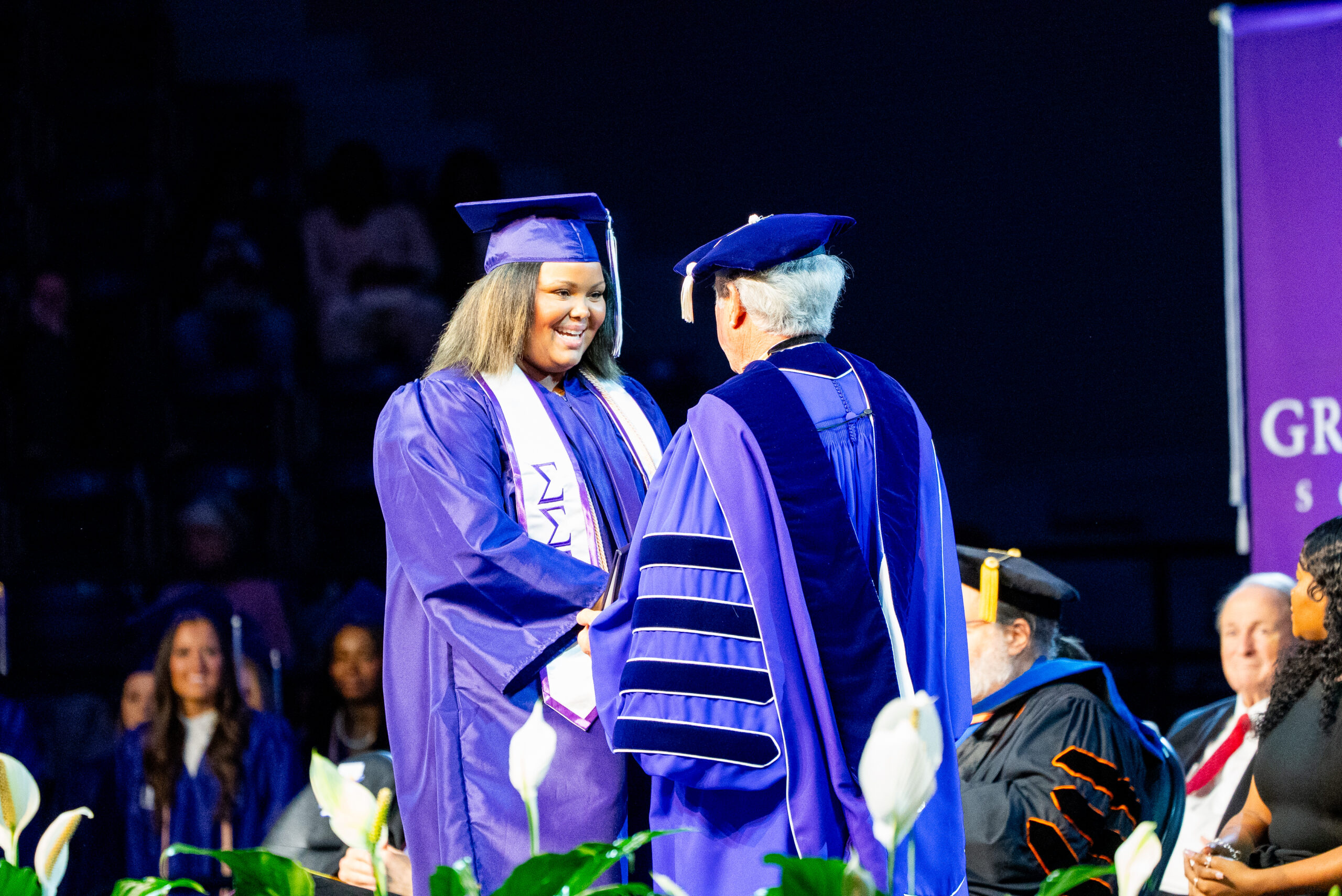 An NSU graduate receives her diploma from Jimmy Genovese, president of Northwestern State University
