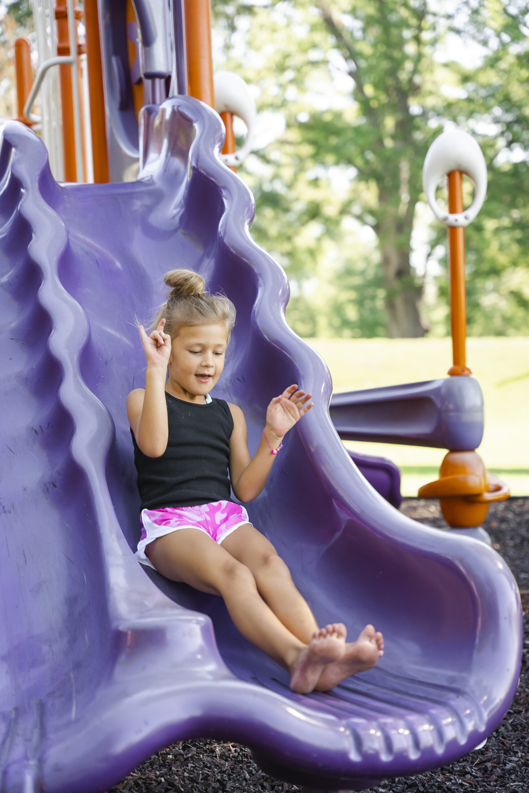 Young child slides down the slide on campus