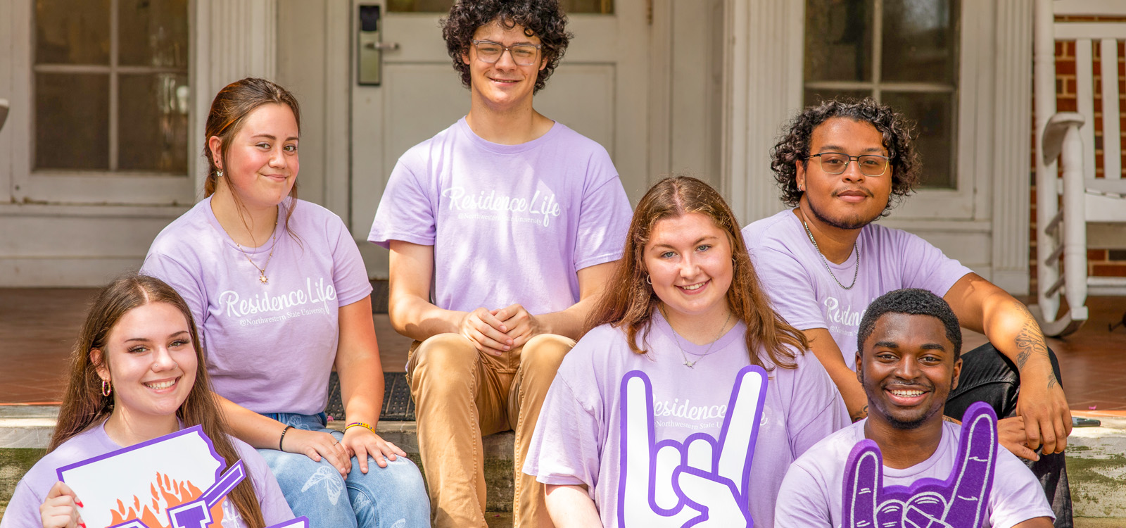 Group of NSU students sitting on steps of Varnado Hall.