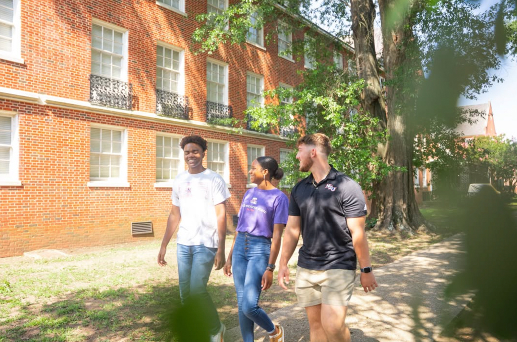 Three NSU students walk through oak trees near Alumni House