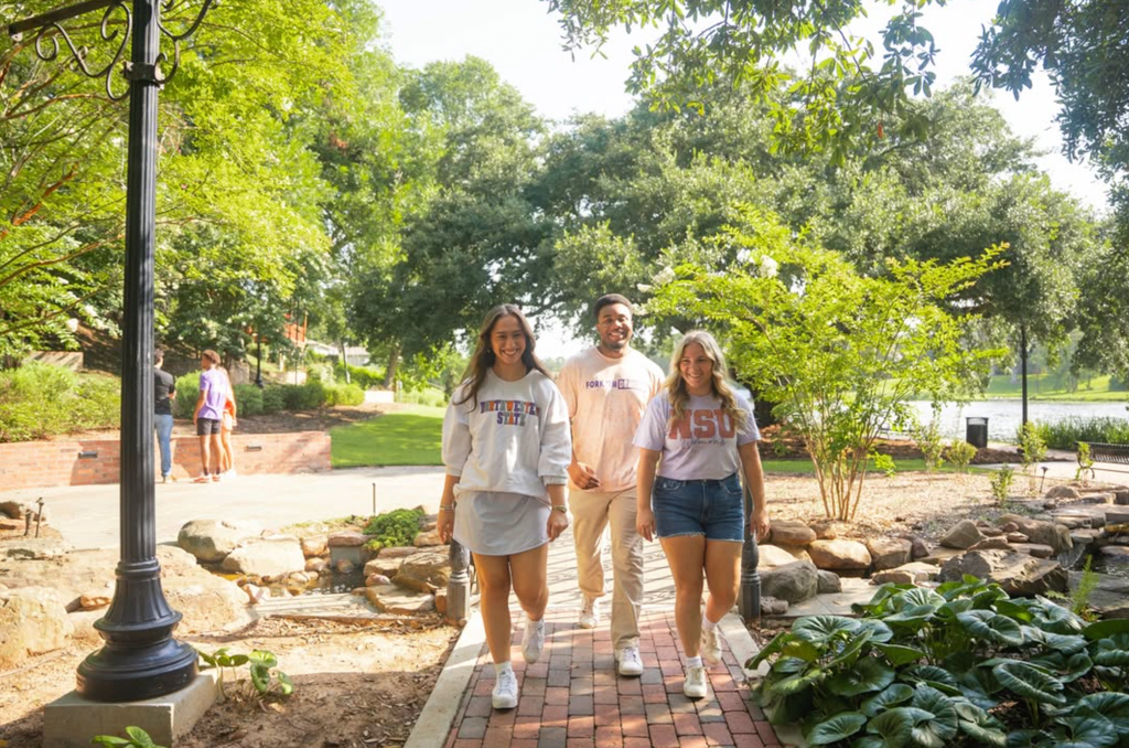 Three NSU student stroll down riverbank in Natchitoches