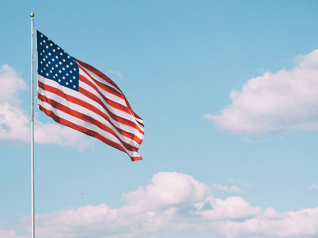 American flag over blue skies and clouds