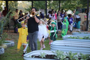Gabriel Camargo Patron, with his dad Carlos on trombone, led NSU Elementary Lab first graders in a second line through the school garden to the tune of “When the Seeds Get Planted Snug.”