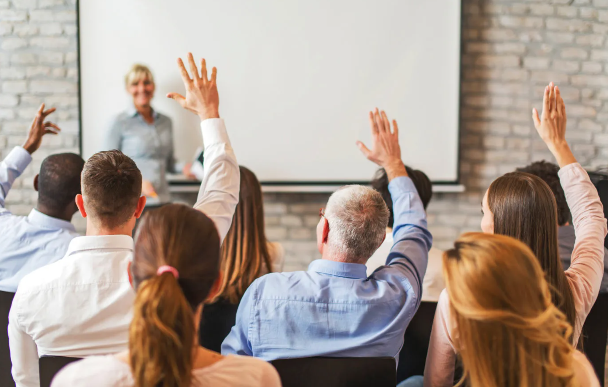 Image of Professionals gathered in a meeting, smiling and asking questions.