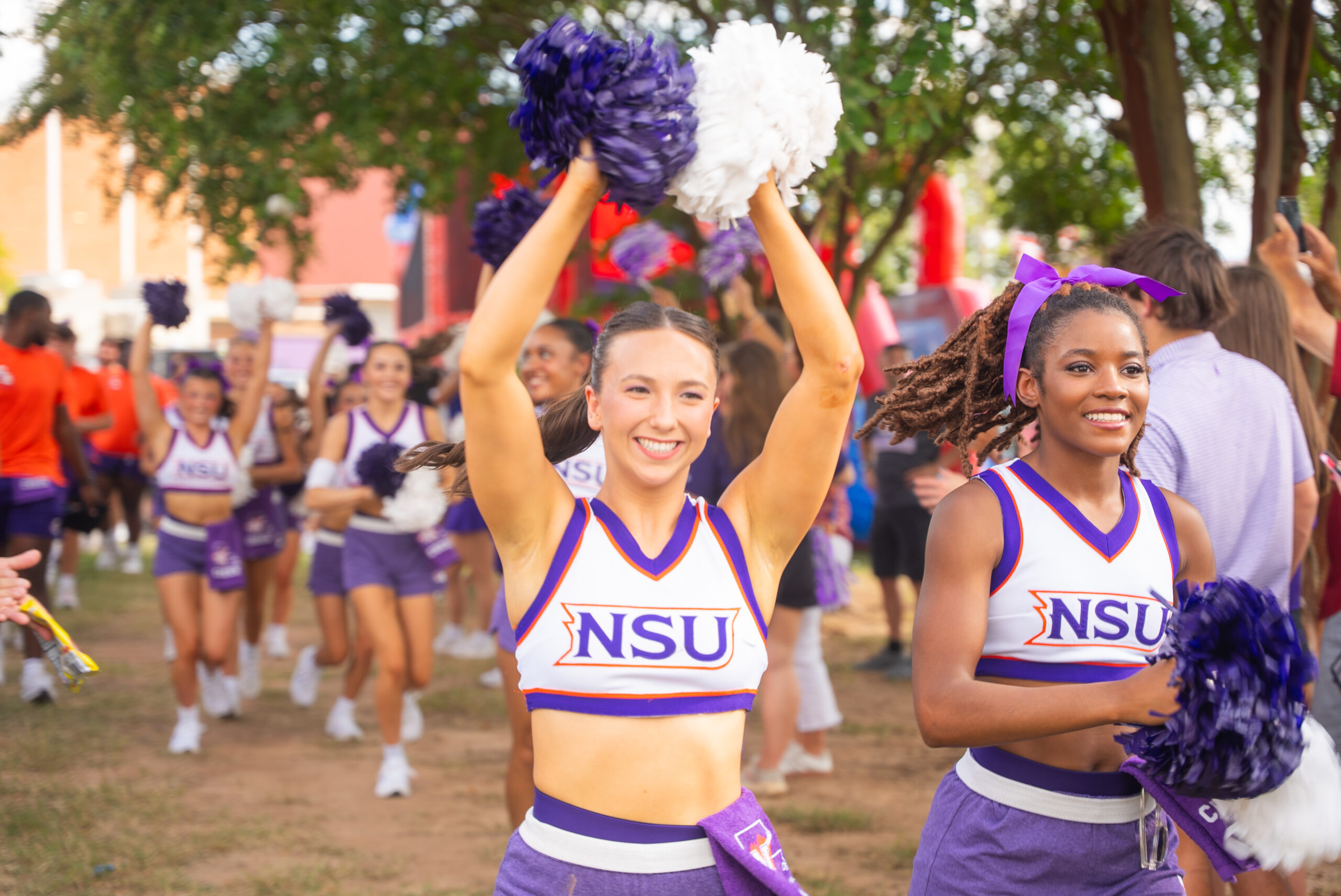 Two cheerleaders with pom poms raised