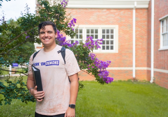 NSU student standing with books on campus.