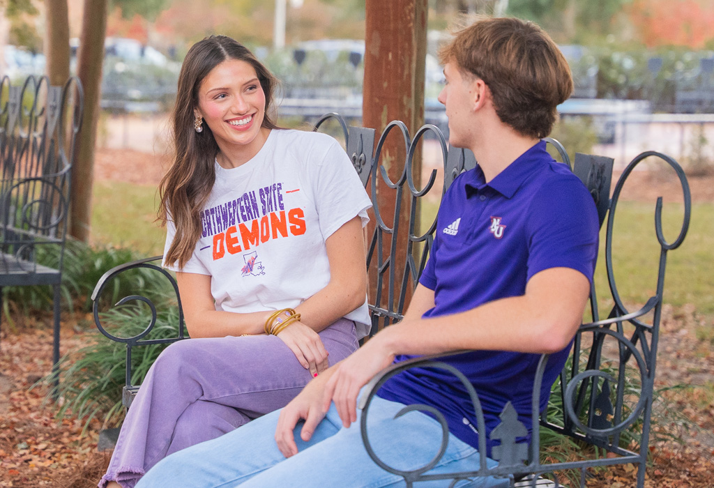 Two NSU students sitting on bench in Alumni Plaza.