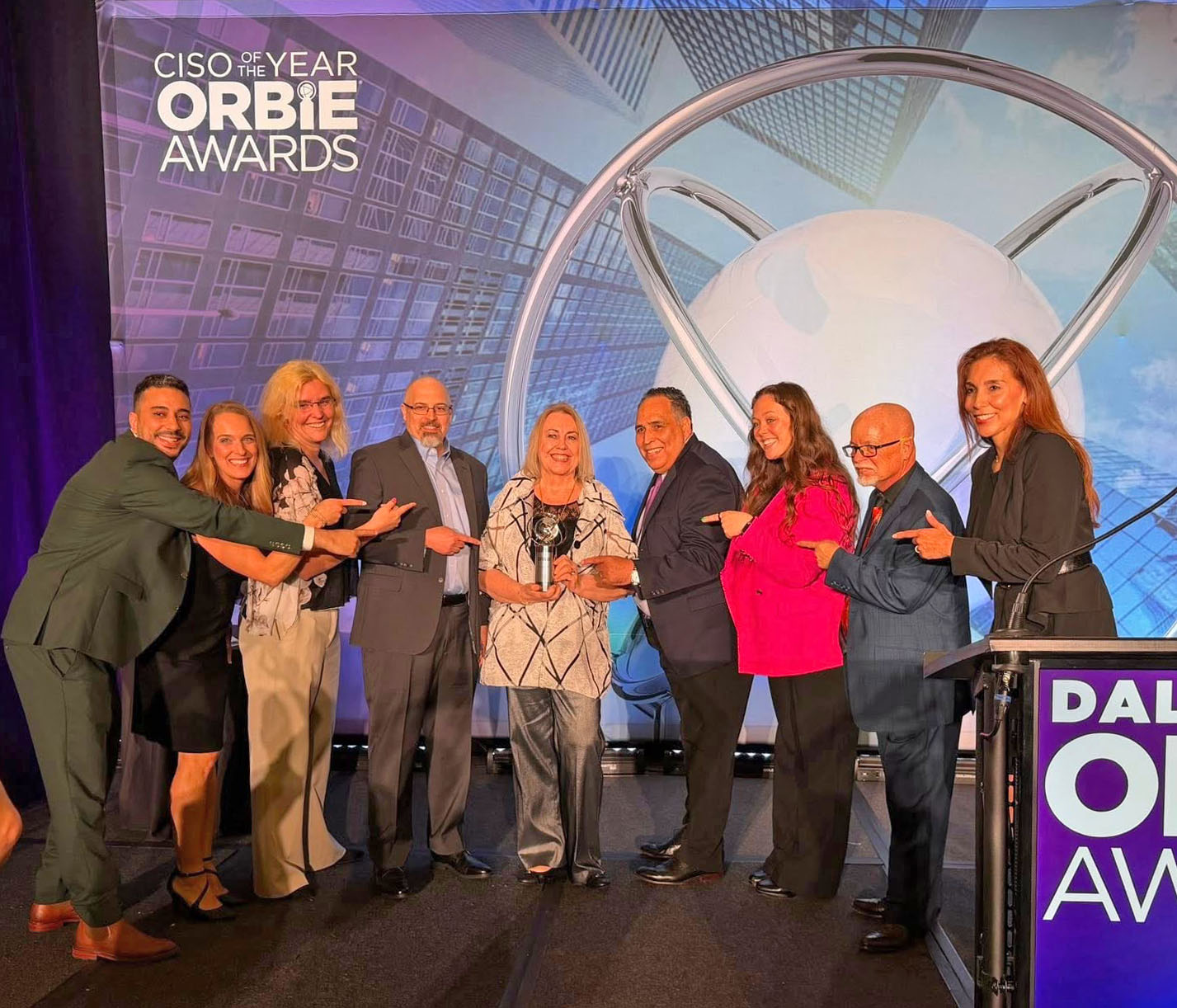 Mignona Coté was congratulation by colleagues on receiving the 2026 DallasCISO ORBIE Award. From left are George Mekhail (Toyota Financial), Jessica Moore (Inspire), Emily Andes (Infor), Derek Bush (Infor), Cote’ (Infor), Carlos Ramirez (Infor), Joe Czabajski (Citi), Kaitlyn Seykora (Infor) and Lourdes Gipson (Inspire).