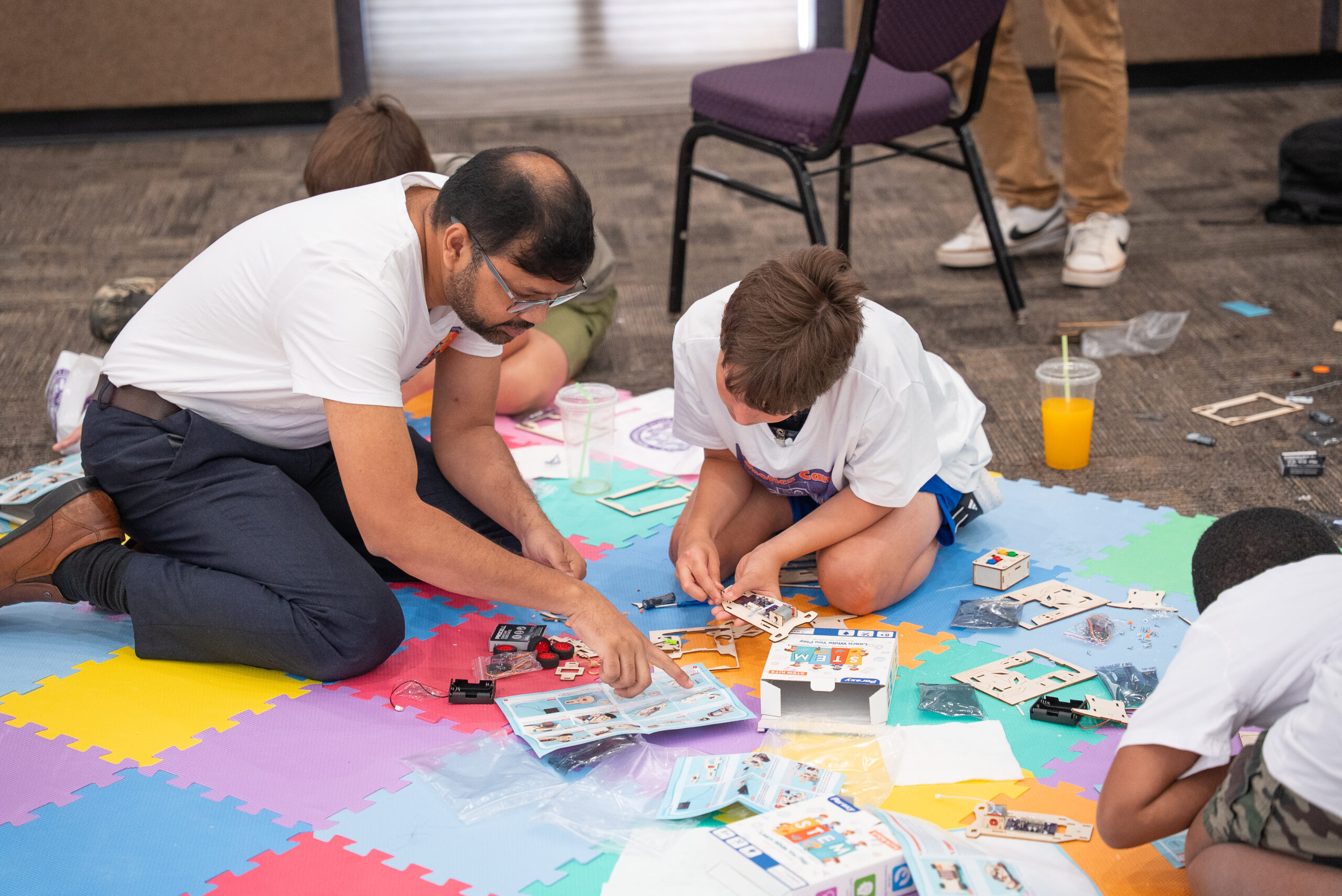 Dr. Shahriar Hossain helps a camper assemble a robotic car during the NSU Robotics Camp.