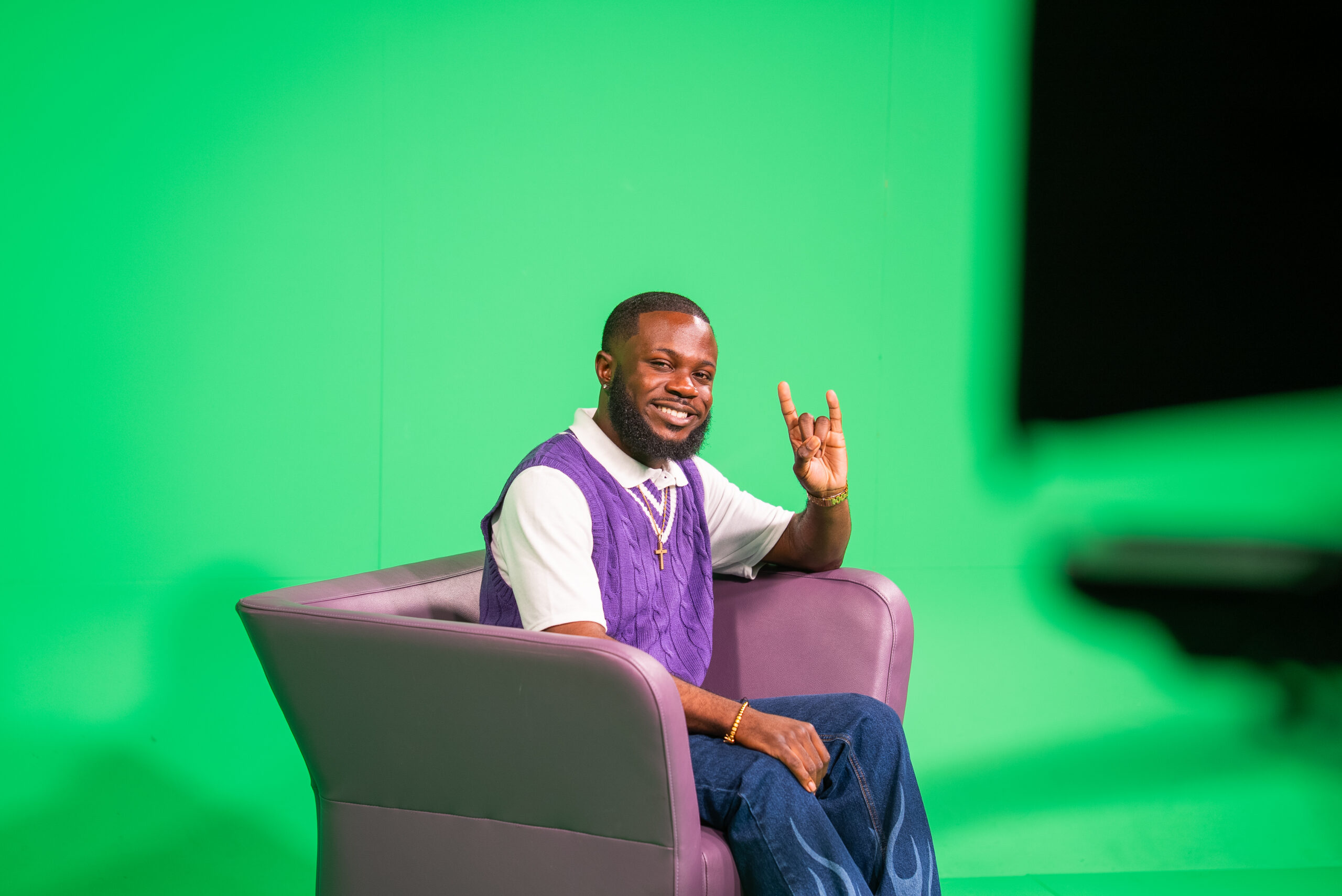 NSU student sitting on a green screen stage