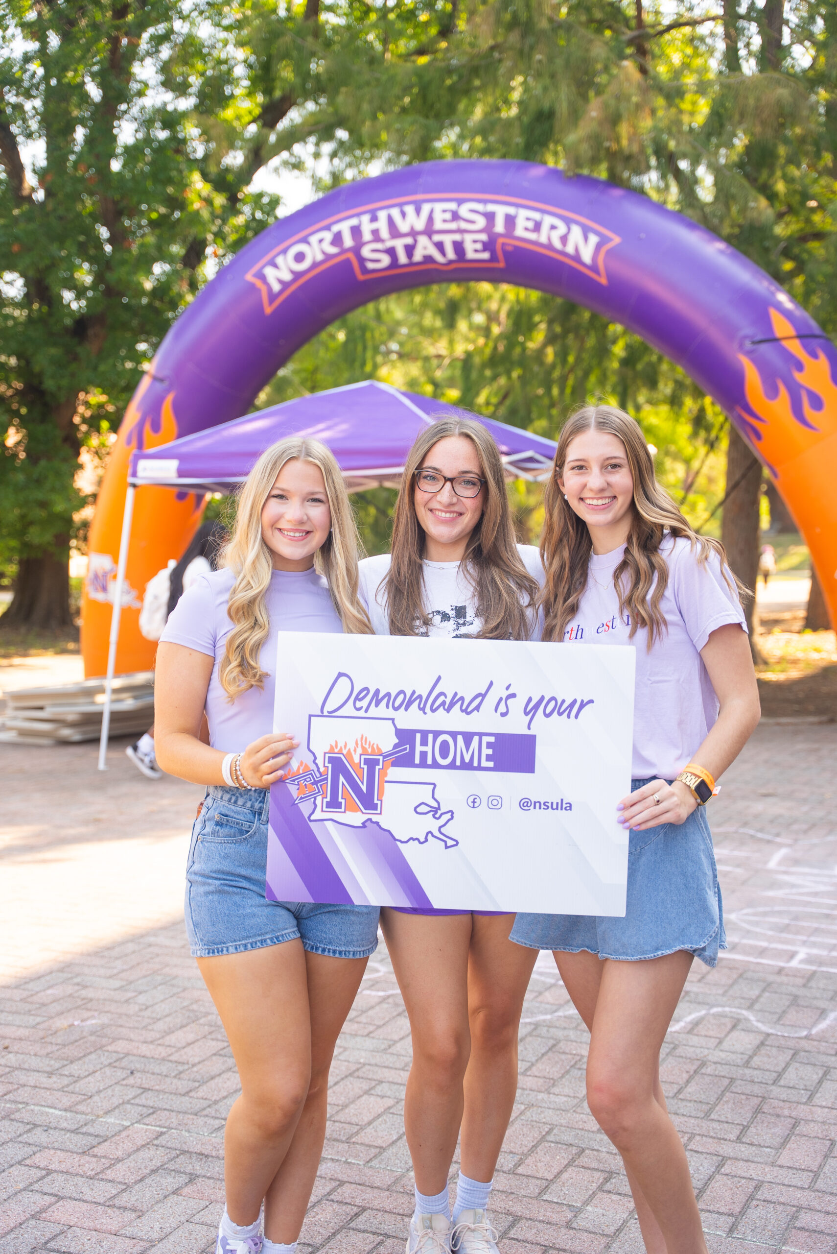 Three female NSU students holding a sign that says 