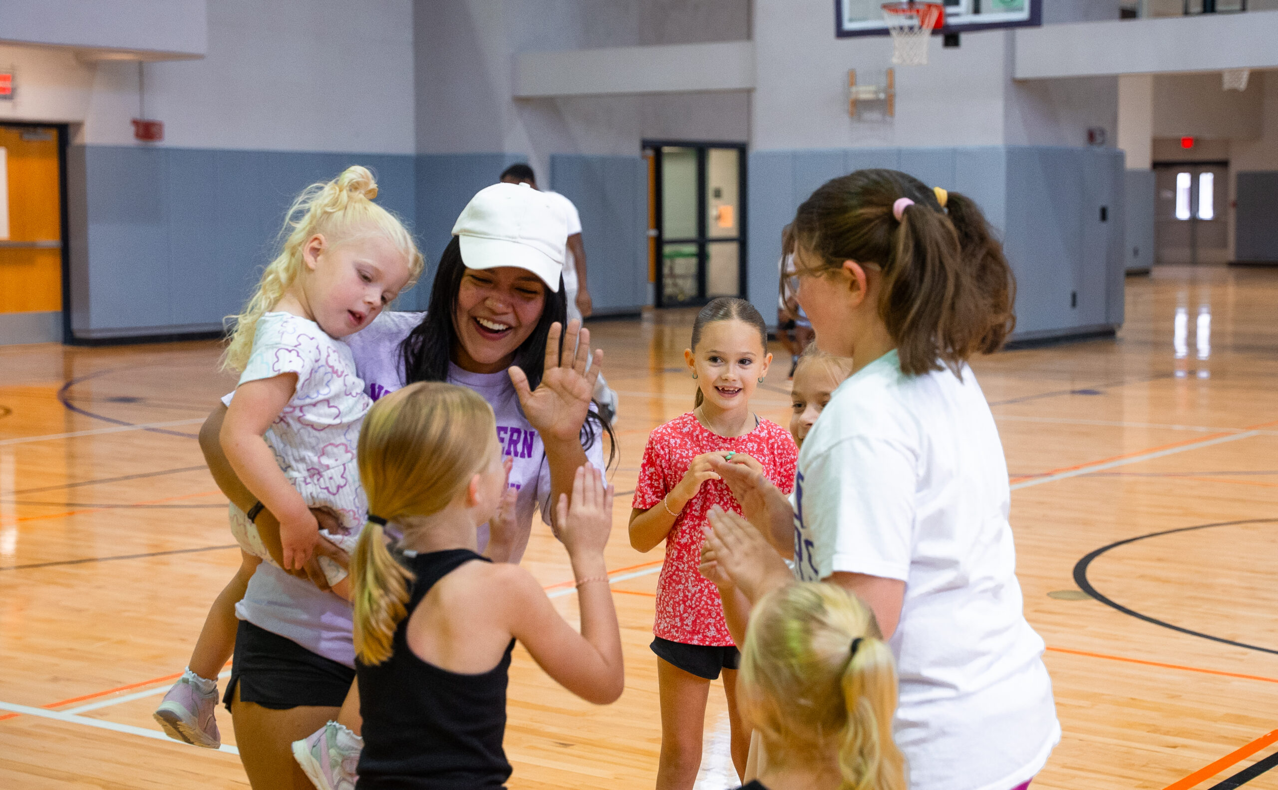 Student worker and camp counselor Dana Baretto plays a hand-clapping game with campers during Northwestern State University's Fun & Fitness Camp at the Dr. Randall J. Webb Wellness, Recreation, and Activity Center.