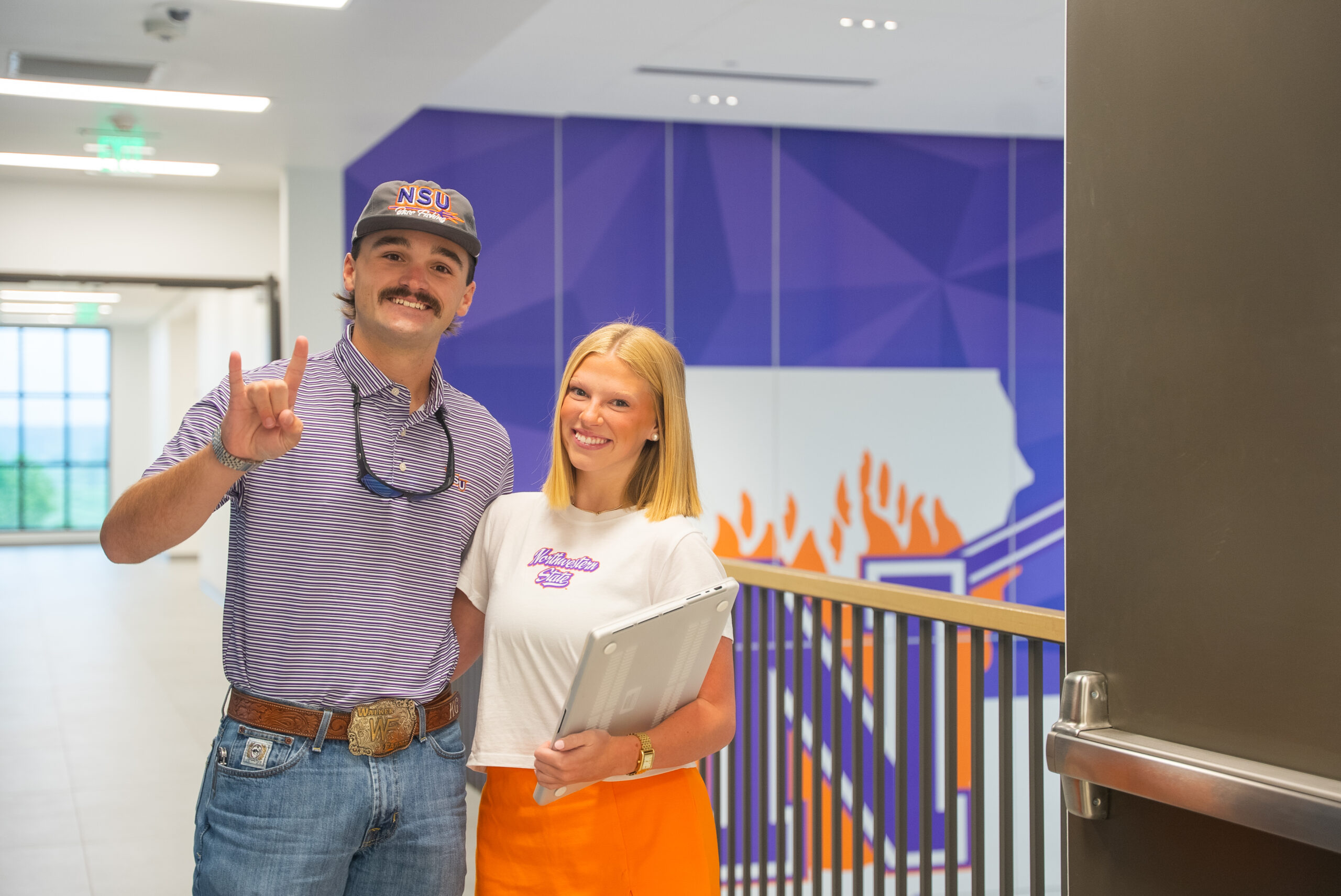 Two NSU students standing next to a NSU logo