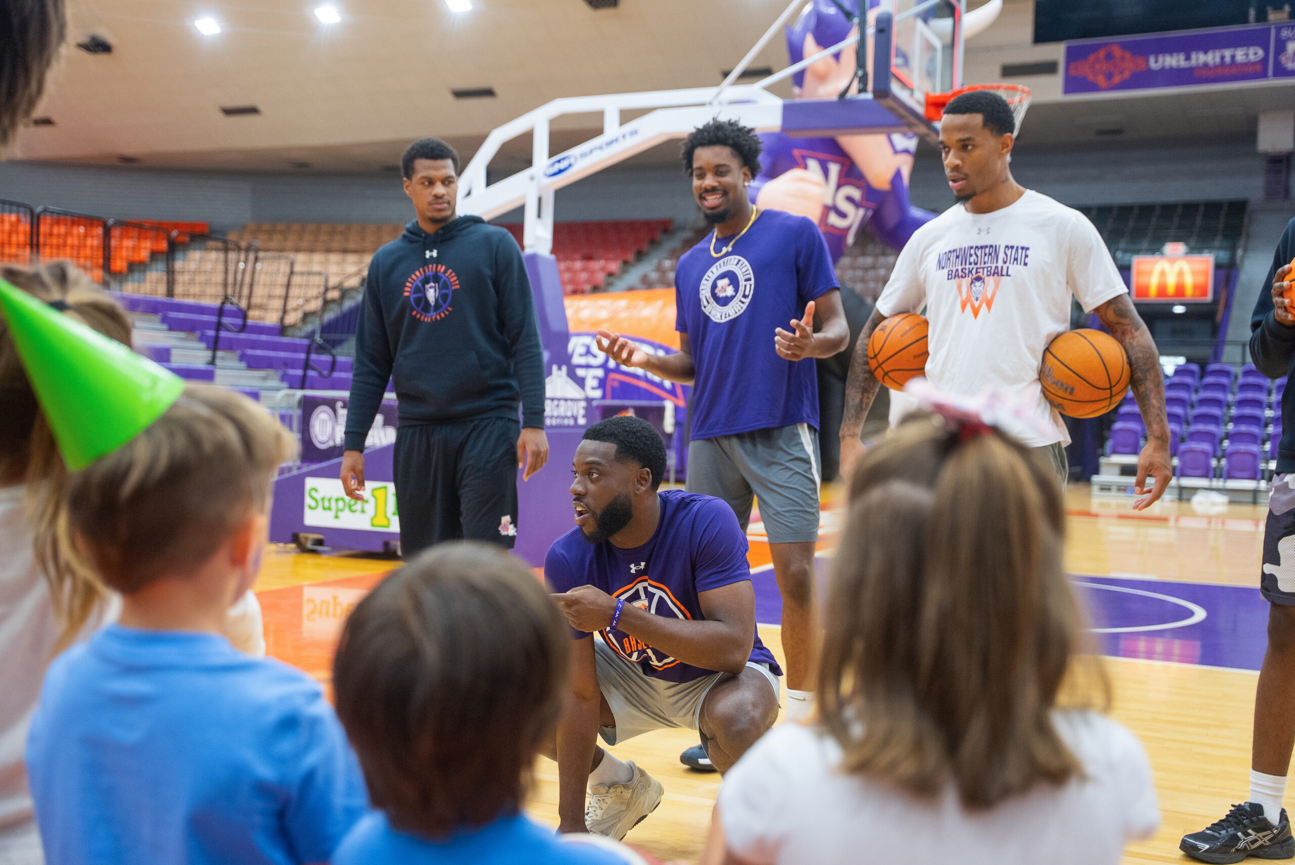 NSU men’s basketball players Kordrick Turner, Isaiah Vick and Dionjahe Thomas, from left, and coach Lance Erving interact with preschoolers from Northwestern State University’s Child Development Center during a visit to Prather Coliseum on Oct. 21.